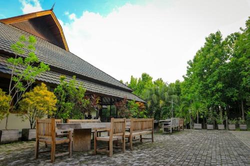 a table and benches in front of a building at Hotel & Villa Bukit Indah Saumlaki by LeGreen 