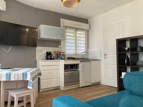 cocina pequeña con mesa y sofá azul en La Capitane en La Baule