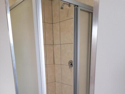 a shower with a glass door in a bathroom at Zithei Lodge in Lombardskop Settlement