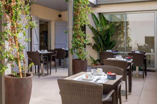 a restaurant with tables and chairs and plants at Best Western Hotel & SPA Coeur De Cassis in Cassis
