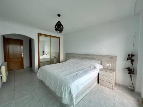 ein weißes Schlafzimmer mit einem großen Bett und einem Spiegel in der Unterkunft Viviendas Paragüero vista al mar in Portonovo