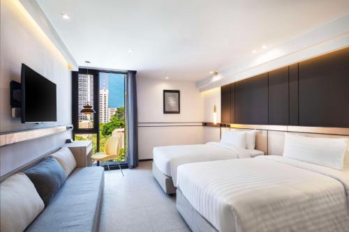 a hotel room with two beds and a flat screen tv at Best Western Ratchada Hotel in Bangkok