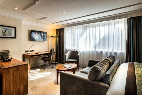 a hotel room with a couch and a desk at The Marble Arch Hotel, by Thistle in London