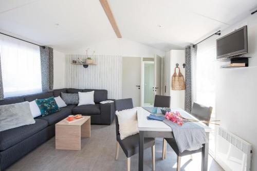 uma sala de estar com um sofá e uma mesa em Camping Au Pré de l'Étang em Sainte-Foy