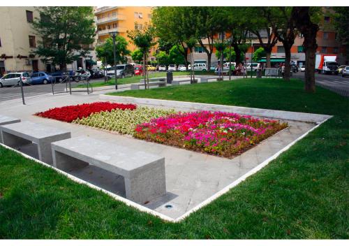 a bench in a park with flowers in the grass at Piazza Vescovio Apartment in Rome