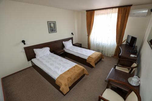 a hotel room with two beds and a desk at Hotel Dusan si Fiul Resita Sud in Reşiţa