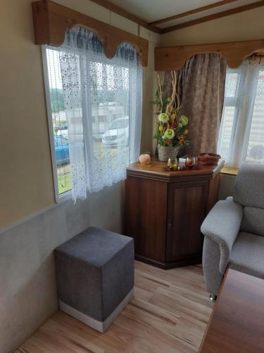 ein Wohnzimmer mit einem Stuhl, einem Tisch und Fenstern in der Unterkunft Mobilní dům Rimini a Monaco v kempu ve Výrovicích in Výrovice
