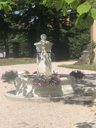 una estatua de una fuente con flores en un parque en Le manoir de la Source, en Cronat