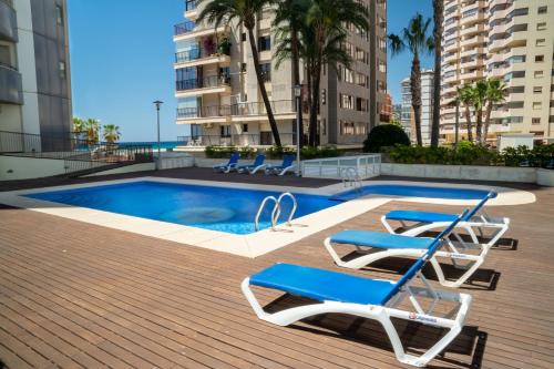 a swimming pool with two chairs and a pair ofvisorvisor at Apartamentos Vista Bella in Calpe