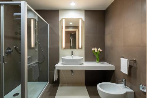 a bathroom with a sink and a toilet and a shower at UNAHOTELS Bologna San Lazzaro in San Lazzaro di Savena