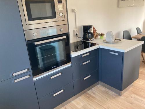 eine Küche mit einer Mikrowelle und einem blauen Schrank in der Unterkunft Maison de vacances Bréhal in Bréhal