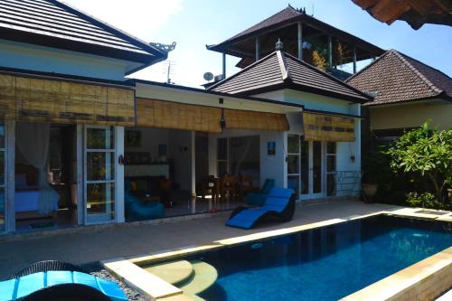 a villa with a swimming pool in front of a house at Ratna Villa in Ubud