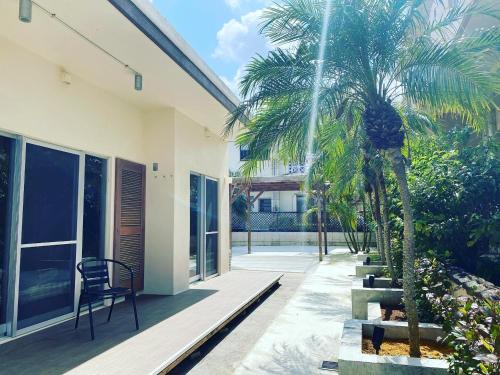 a patio with palm trees and a chair on a house at Seven Residence Music in Nago