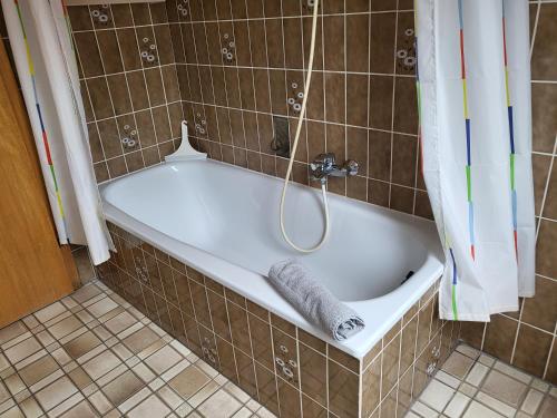 La salle de bains carrelée est pourvue d'une baignoire et d'une serviette. dans l'établissement Ferienwohnung "Ostergeest", à Sankt Peter-Ording