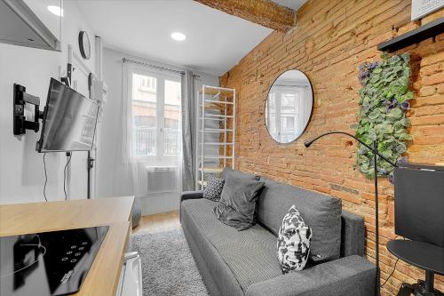 un salon avec un canapé et un mur de briques dans l'établissement Getaway For 2 Beautiful Studio Near The Garonne, à Toulouse