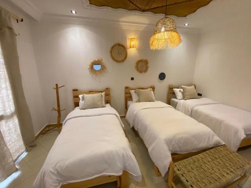 a room with three beds and a chandelier at West coast surf house in Imsouane