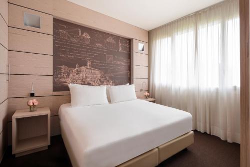 サン・ラッザロ・ディ・サーヴェナにあるUNAHOTELS Bologna San Lazzaroの白い大型ベッドと壁が備わるベッドルーム1室が備わります。