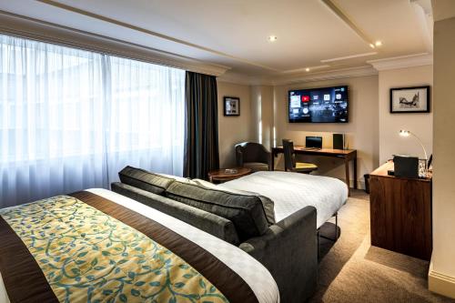 a hotel room with a bed and a desk at The Marble Arch Hotel, by Thistle in London