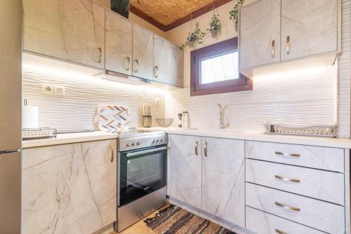 a kitchen with white cabinets and an oven at Relaxing StoneHouse Kamara with Jacuzzi in Pómbia