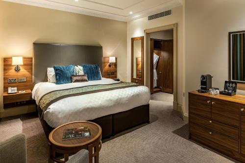 a bedroom with a large bed with blue pillows at The Marble Arch Hotel, by Thistle in London