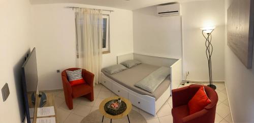 a small bedroom with a bed and two chairs at Apartmani Lovre i Zara in Zadar