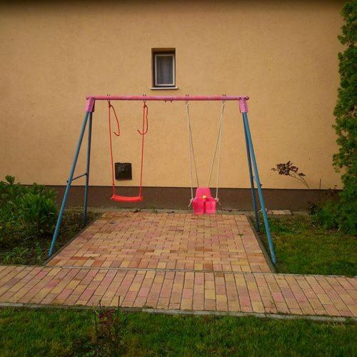 a pink swing set in front of a building at Sweet Home Apartman in Hajdúszoboszló