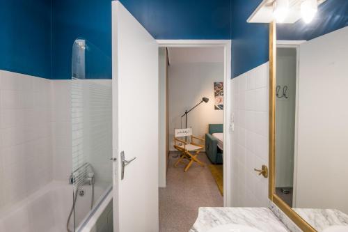 een badkamer met blauwe muren, een bad en een wastafel bij Cardabelle - Joli appt pour 2 avec parking privé in Millau