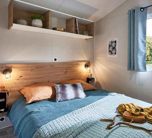 um quarto com uma cama grande e um cobertor azul em Camping Au Pré de l'Étang em Sainte-Foy