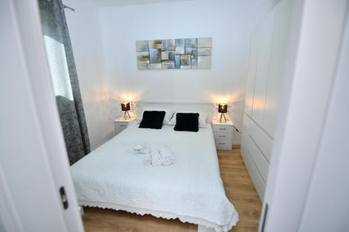 Un dormitorio con una cama blanca con dos vasos. en Palomino apartment, en Sinj