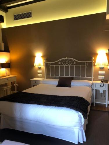 a bedroom with a large white bed with two lights at Hotel Torre Zumeltzegi in Oñate