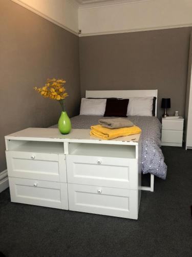 a bed with a white dresser with a vase on it at Cosy studio in Mill Hill