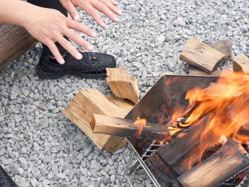 a person is standing next to a campfire at 丘の上から海が見える一棟貸しヴィラ しまいろ長手 in Nagate