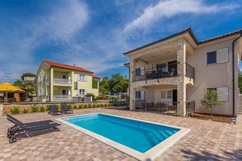a villa with a swimming pool in front of a house at Apartman Sandra in Malinska