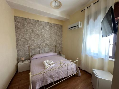 um pequeno quarto com uma cama e uma televisão em Baia dei turchi locazione turistica em Realmonte