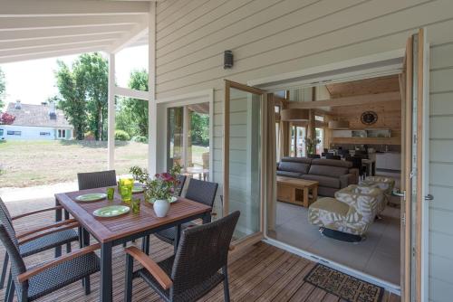 une véranda avec une table et des chaises dans l'établissement Chalet Bien Etre - 150m² - Avec Sauna & Balnéo - Les 4 saisons - Lac de Chalain, à Marigny