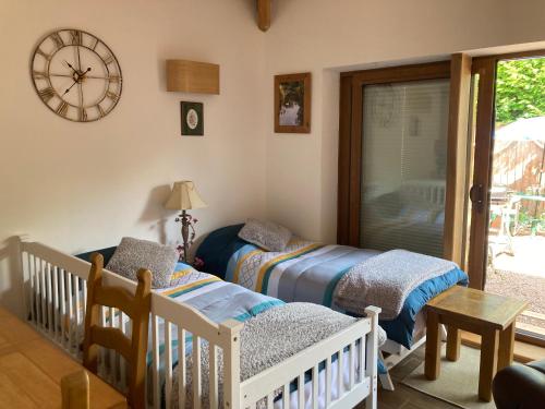 a nursery with two beds and a clock on the wall at Charming Gnome Cottage in Devon near Sidmouth in Ottery Saint Mary