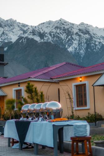 a table with four chairs and a mountain in the background at Dynasty Hotel Skardu in Skardu