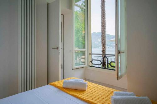 a bedroom with a window and a bed with towels on it at Villa Vescovo Appartamento con accesso al lago in Orta San Giulio