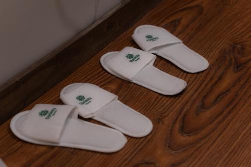three pairs of white slippers on a wooden floor at Dynasty Hotel Skardu in Skardu