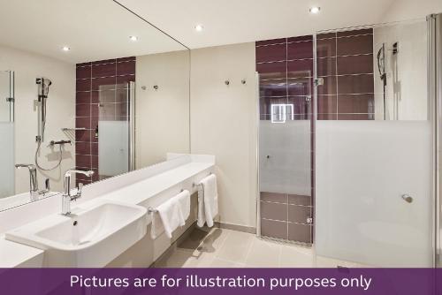 a white bathroom with a sink and a shower at Premier Inn Freiburg City Süd in Freiburg im Breisgau
