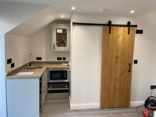 a kitchen with a wooden door in a room at Robin's Nest - a self contained detached annex with sky sports & movies in Newborough