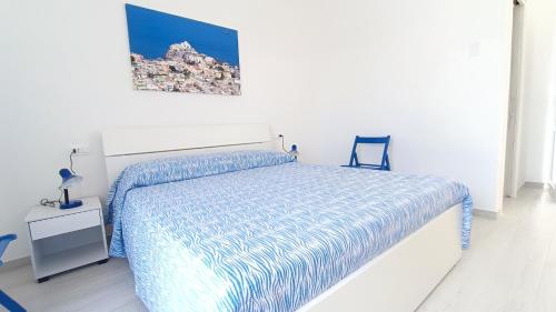 a white bedroom with a bed and a chair at Passariello in Ischia