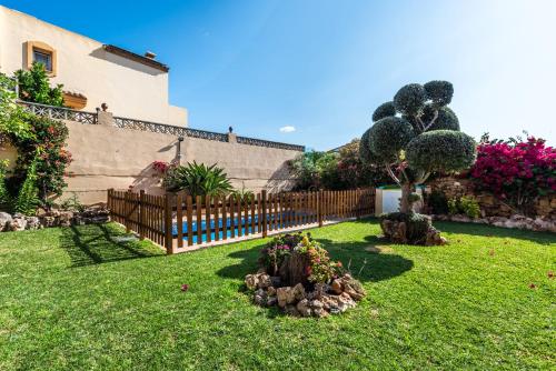 a yard with a fence and a tree and flowers at Chalet Marbella Beach I in Marbella