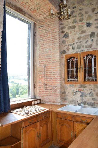 een keuken met houten kasten, een raam en een wastafel bij Château de Gorze in Germolles-sur-Grosne