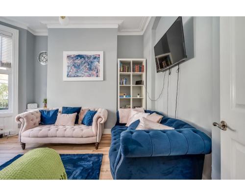 a living room with two blue couches and a tv at Central Belfast Apartments Ballyhackamore in Belfast