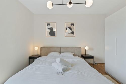 ein weißes Schlafzimmer mit einem großen Bett mit zwei Lampen in der Unterkunft Gem in Historic District Belval in Sanem