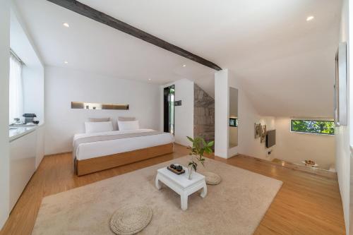 a white bedroom with a bed and a table at The Bivou Lijiang in Lijiang