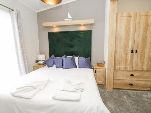 ein Schlafzimmer mit einem großen weißen Bett mit blauen Kissen in der Unterkunft 48 Crosswinds in Bembridge