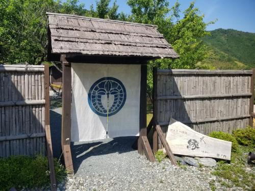 Ochiにあるゲストハウス縁のフェンスの横にある看板の付いた小さな小屋