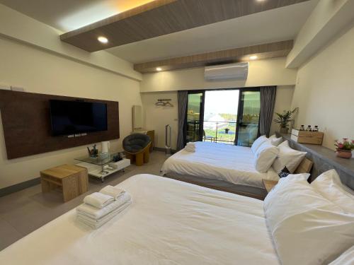 a hotel room with two beds and a flat screen tv at Dongjin Bay B&B in Donggang